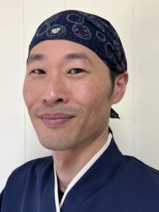 headshot of Kenji Wada looking at the camera with a closed-mouth smile